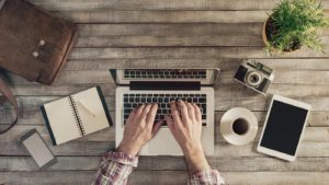 Someone Getting Started On Their Startup Marketing At A Desk With Laptop And Neccesities